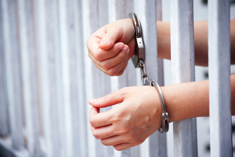 Hands of prisoner in bar jail background