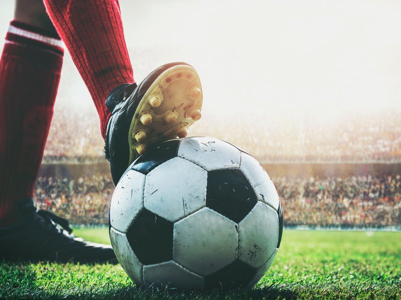 Feet of soccer player tread on soccer ball for kick-off in the stadium