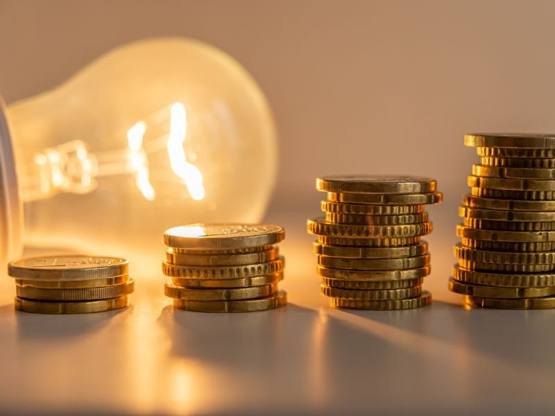 lit light bulb with gold coins