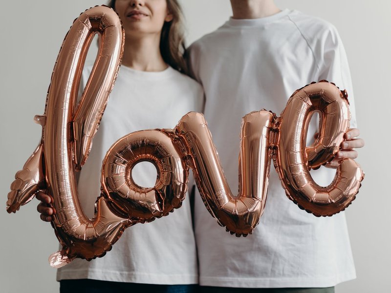 A picture of the a balloon love sign held by two people
