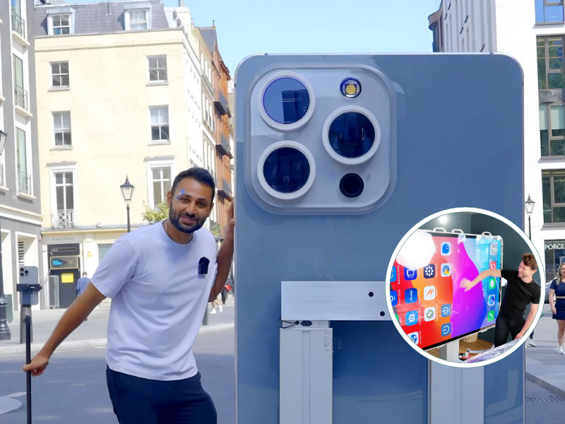 Man standing next to a giant iPhone 15