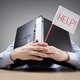 Businessman burying his head under a laptop at work