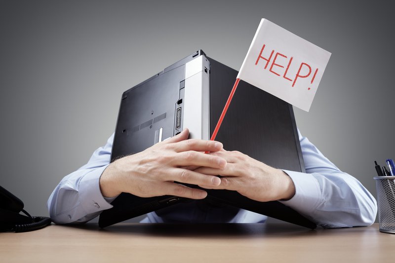 Businessman burying his head under a laptop at work