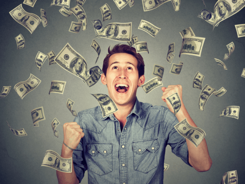 man celebrates as dollar bills fall around him