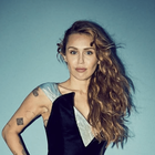Miley Cyrus poses against a blue background