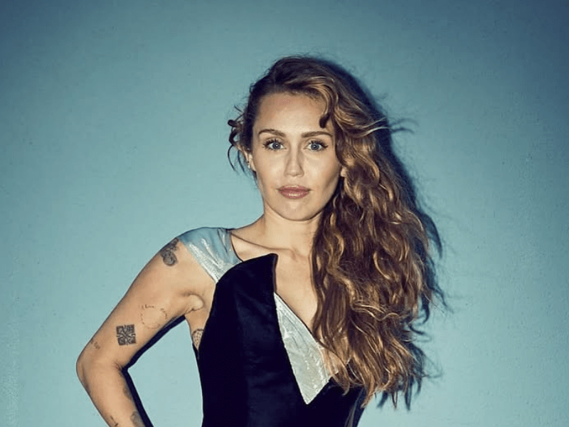 Miley Cyrus poses against a blue background