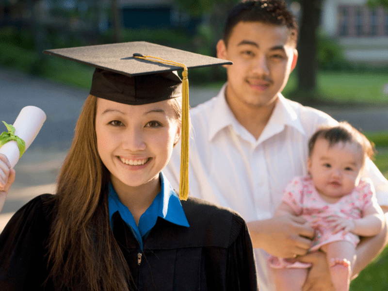woman graduates while husband and baby watch
