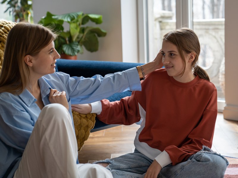 Mother and teen daughter talking while sitting on floor