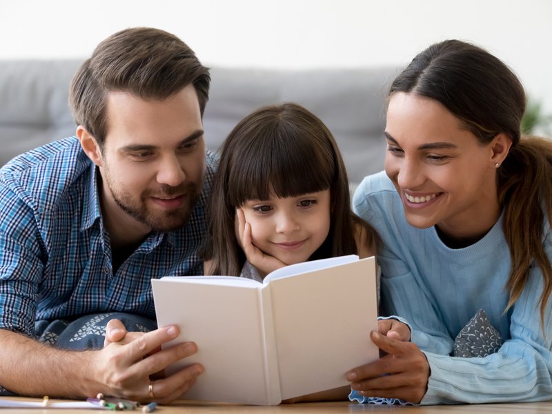 Parents reading a book with daughter