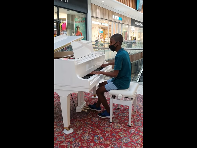 Boy plays piano in mall