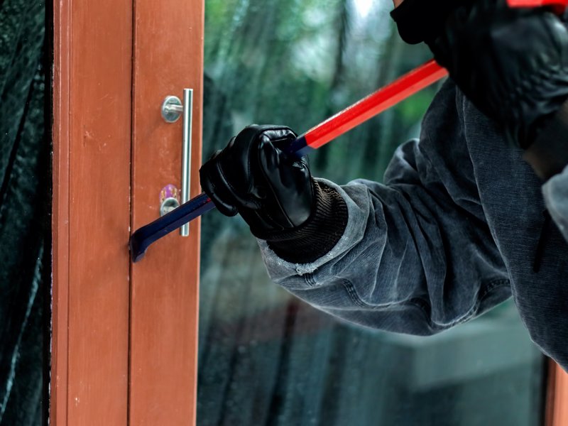 Burglar with crowbar trying to break a door