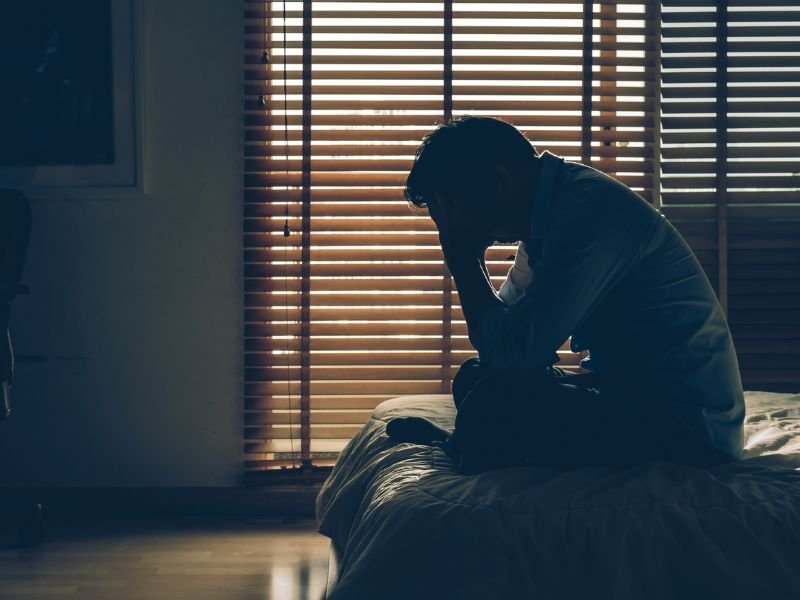Sad businessman sitting on bed