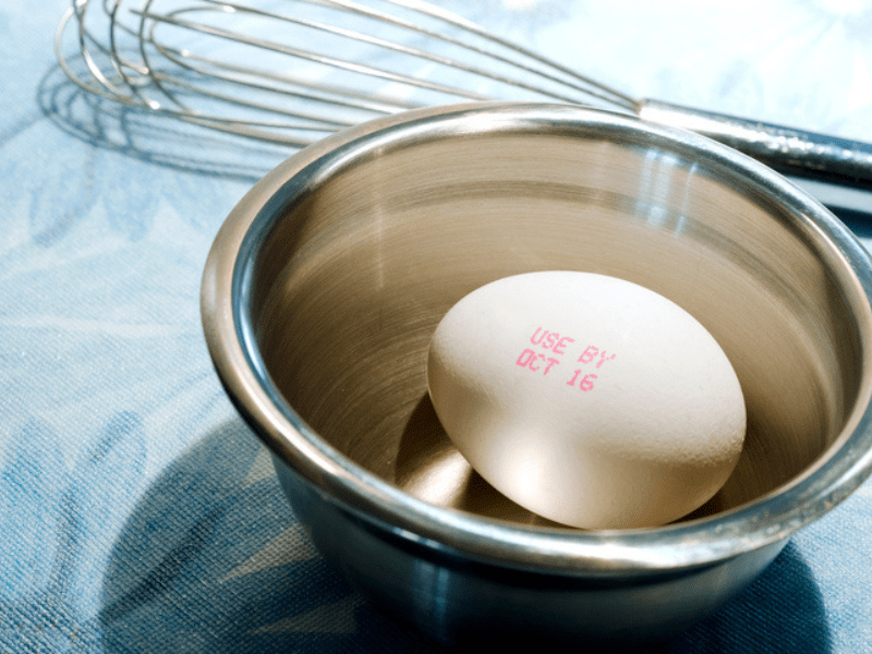 Single egg with an expiration date in a silver bowl