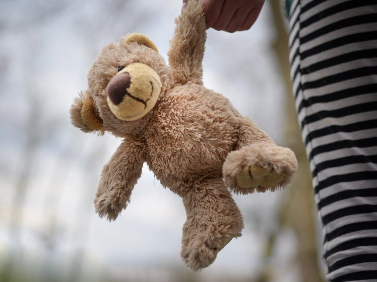 stuffed teddy bear held by a girl child