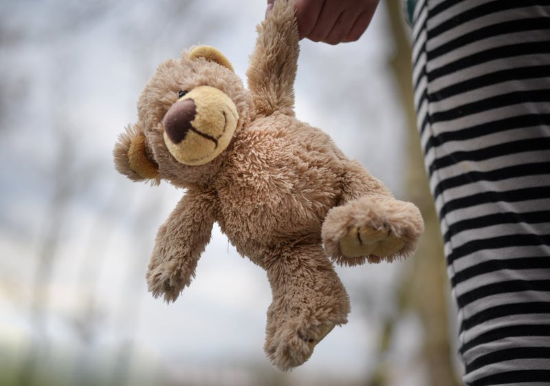 stuffed teddy bear held by a girl child