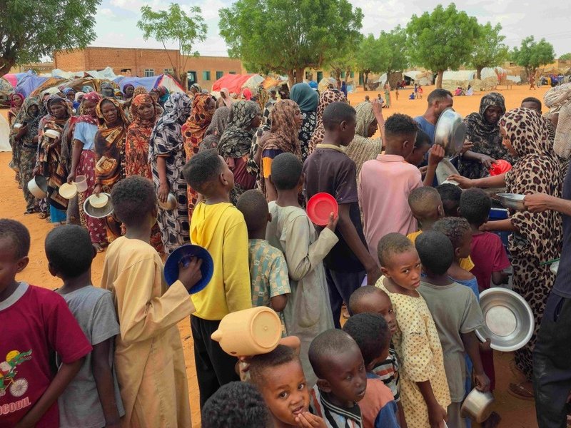Women and children queue to receive free food in Sudan