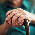A hand of an elderly person holding a walking stick