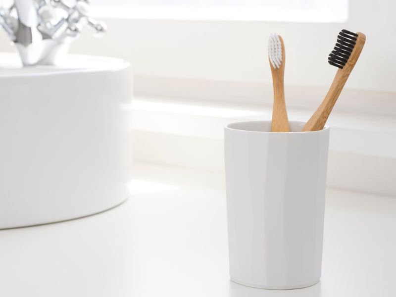 Toothbrushes in cups by basin
