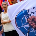 A protestor hold a banner bearing the NATO logo being destructed by a punch during an anti-NATO demonstration in Istanbul