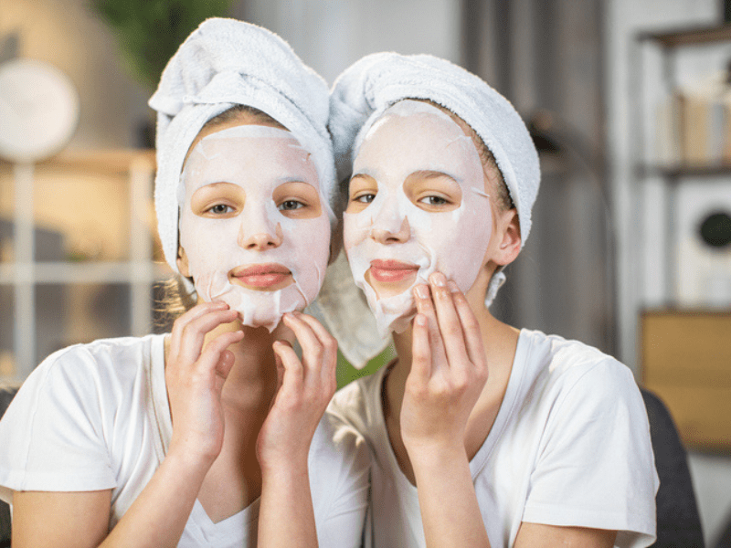 Two girls wearing a white face mask and towels on their head