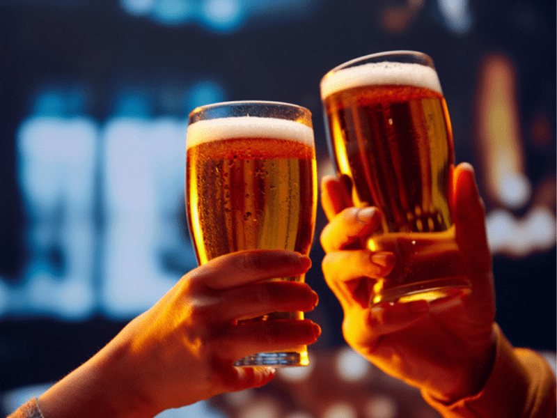 two hands hold foamy big beer glasses