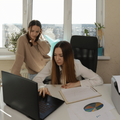 Two women analyse paperwork at an office desk