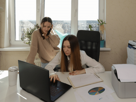 Two women analyse paperwork at an office desk