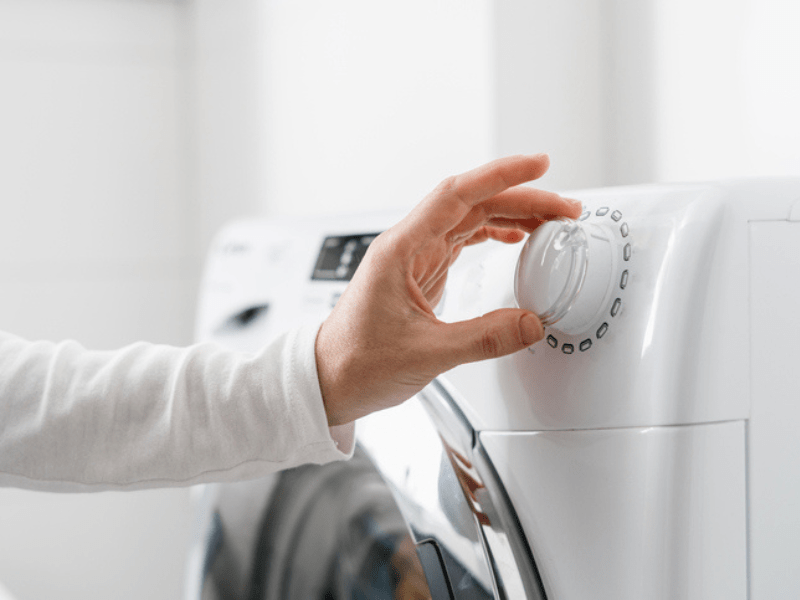 Female hand chooses washing machine mode