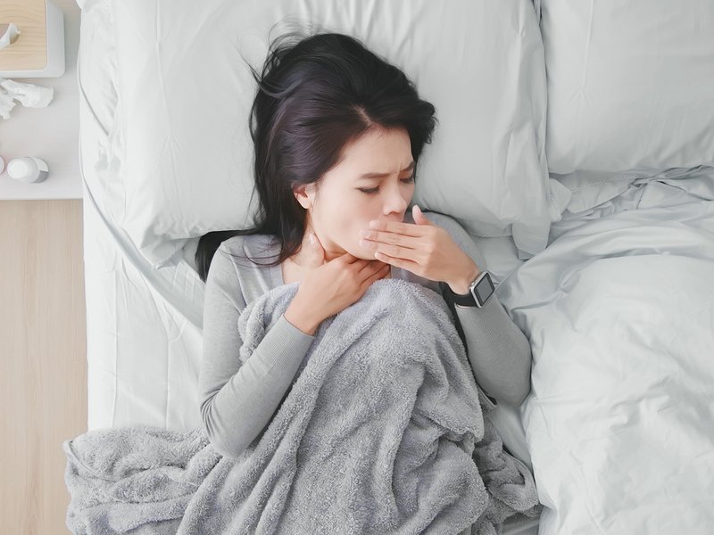 Woman coughing in bed