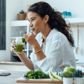 Woman drinks green detox juice in her home kitchen