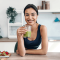 woman drinking a glass of green juice