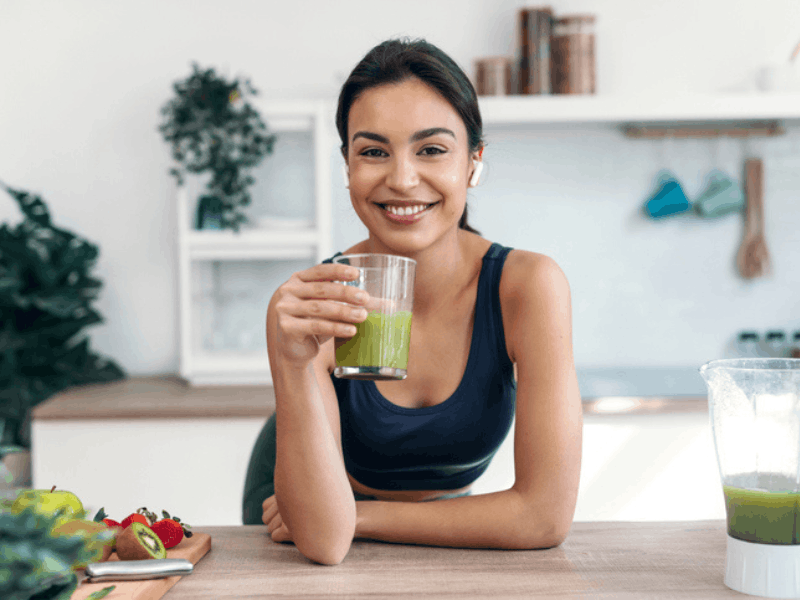 woman drinking a glass of green juice