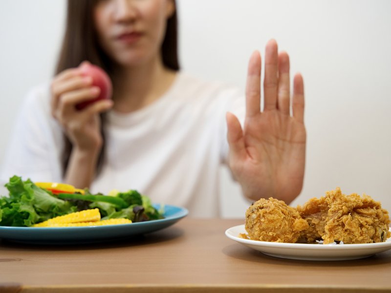 Woman eating vegetables and saying no to meat