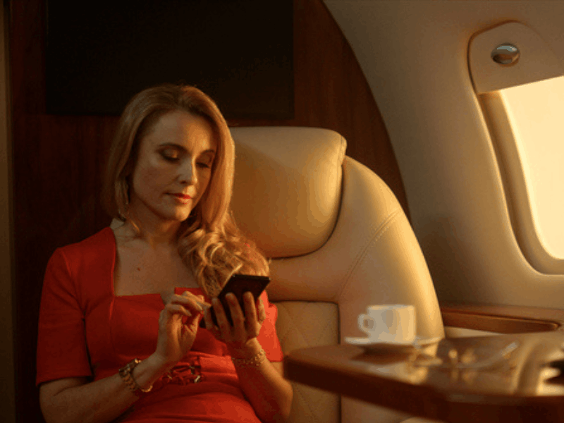 woman looks at her phone while sitting in first class