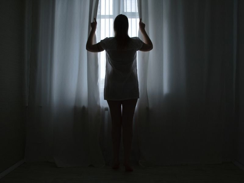 woman opening curtains