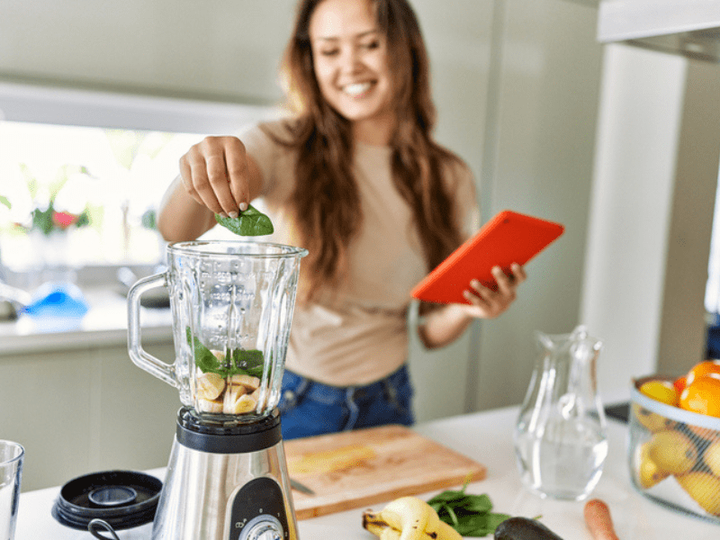 woman puts spinach in a blender while busy in the kitchen-min.png