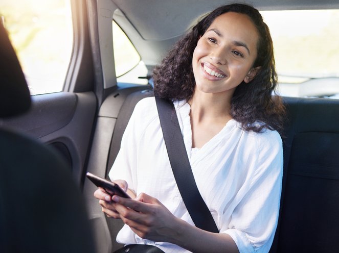 Woman sending a text while sitting in the backseat of a car