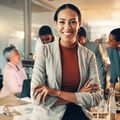 woman sits on an office desk with her arms crossed