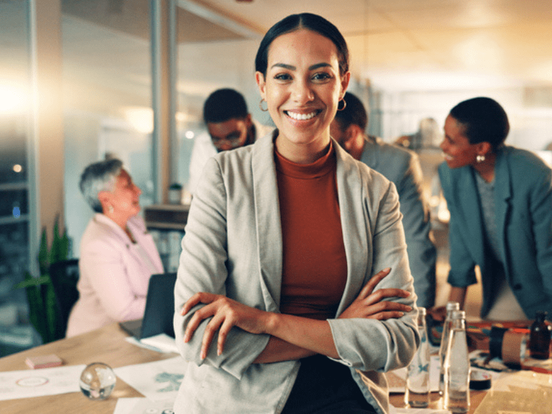woman sits on an office desk with her arms crossed