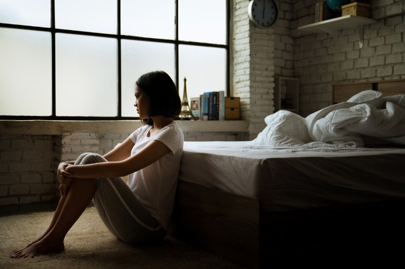 Woman sitting alone in bedroom