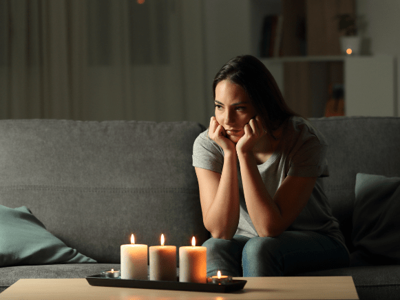 Woman sitting in darkness with candles