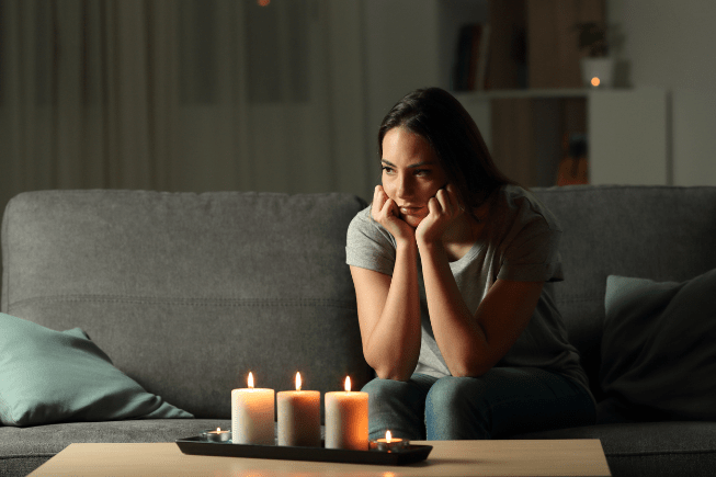 Woman sitting in darkness with candles