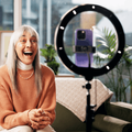 Mature woman content creator with smartphone and ring light