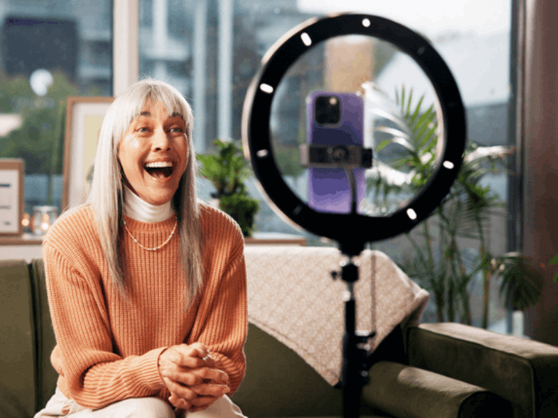 Mature woman content creator with smartphone and ring light