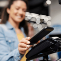 Woman taps smartphone on EFTPOS terminal