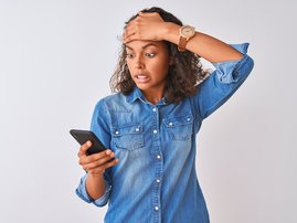 Woman using smartphone stressed with hand on head