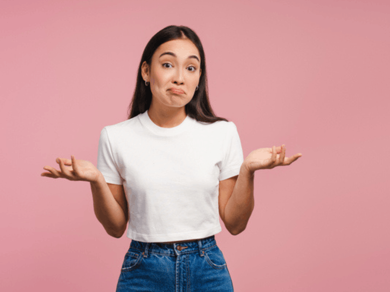 Confused young woman shrugging shoulders