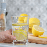 woman holding a glass of water with lemon slices