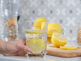 woman holding a glass of water with lemon slices