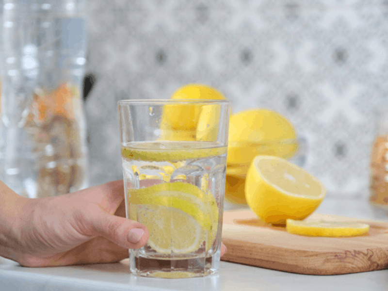 woman holding a glass of water with lemon slices